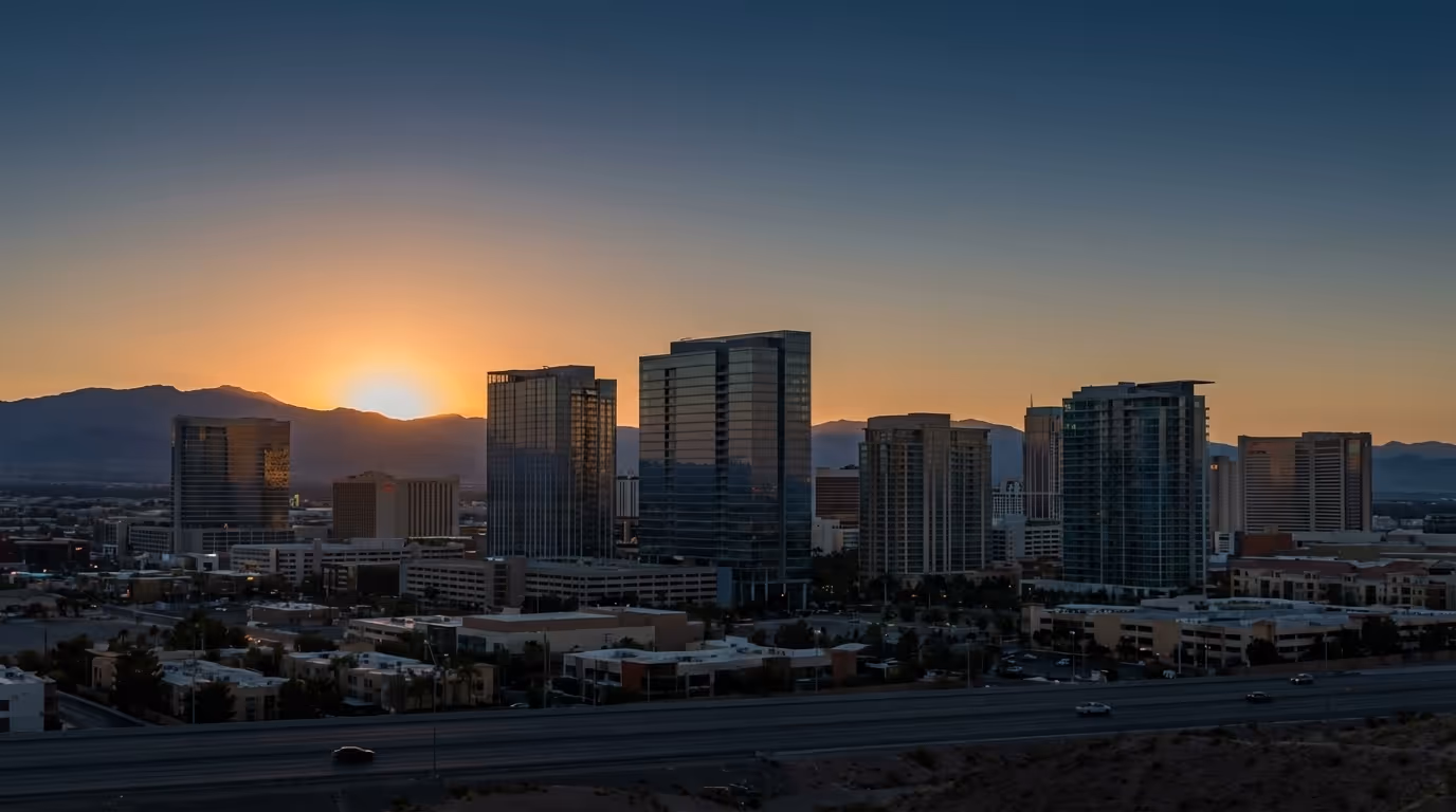 The Las Vegas skyline at sunset, the sun dropping behind the mountains.